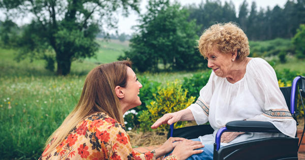 Older Woman In A Wheelchair Being Helped By Younger Woman