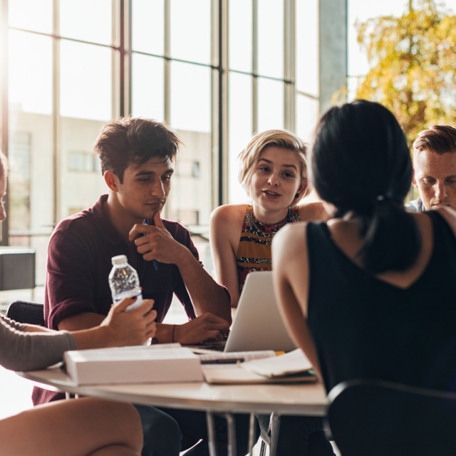 People Sat Around A Table Talking